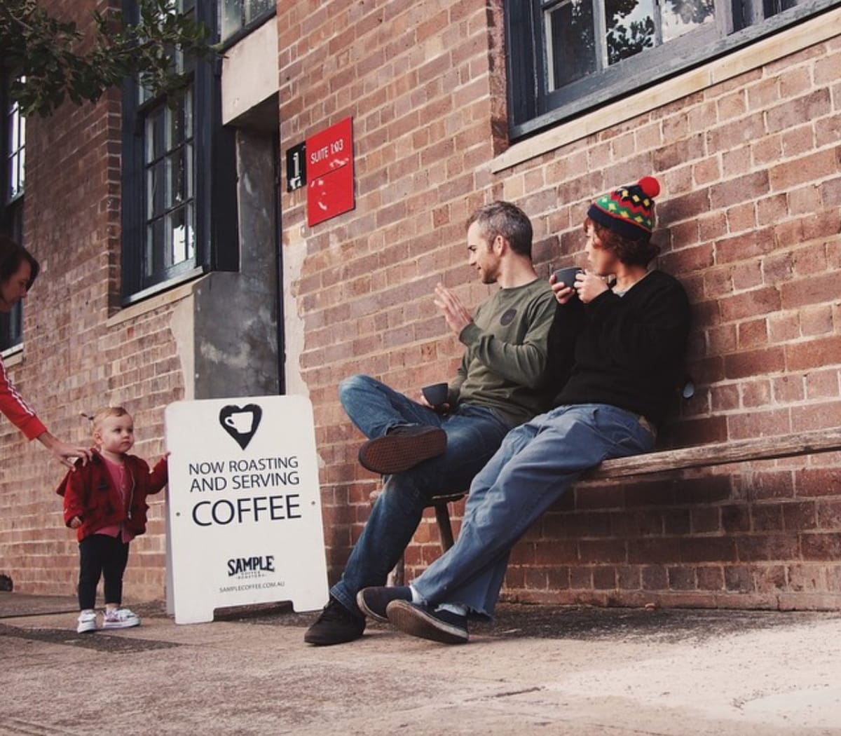 Sample staff having a coffee and waving at a kid on the street.