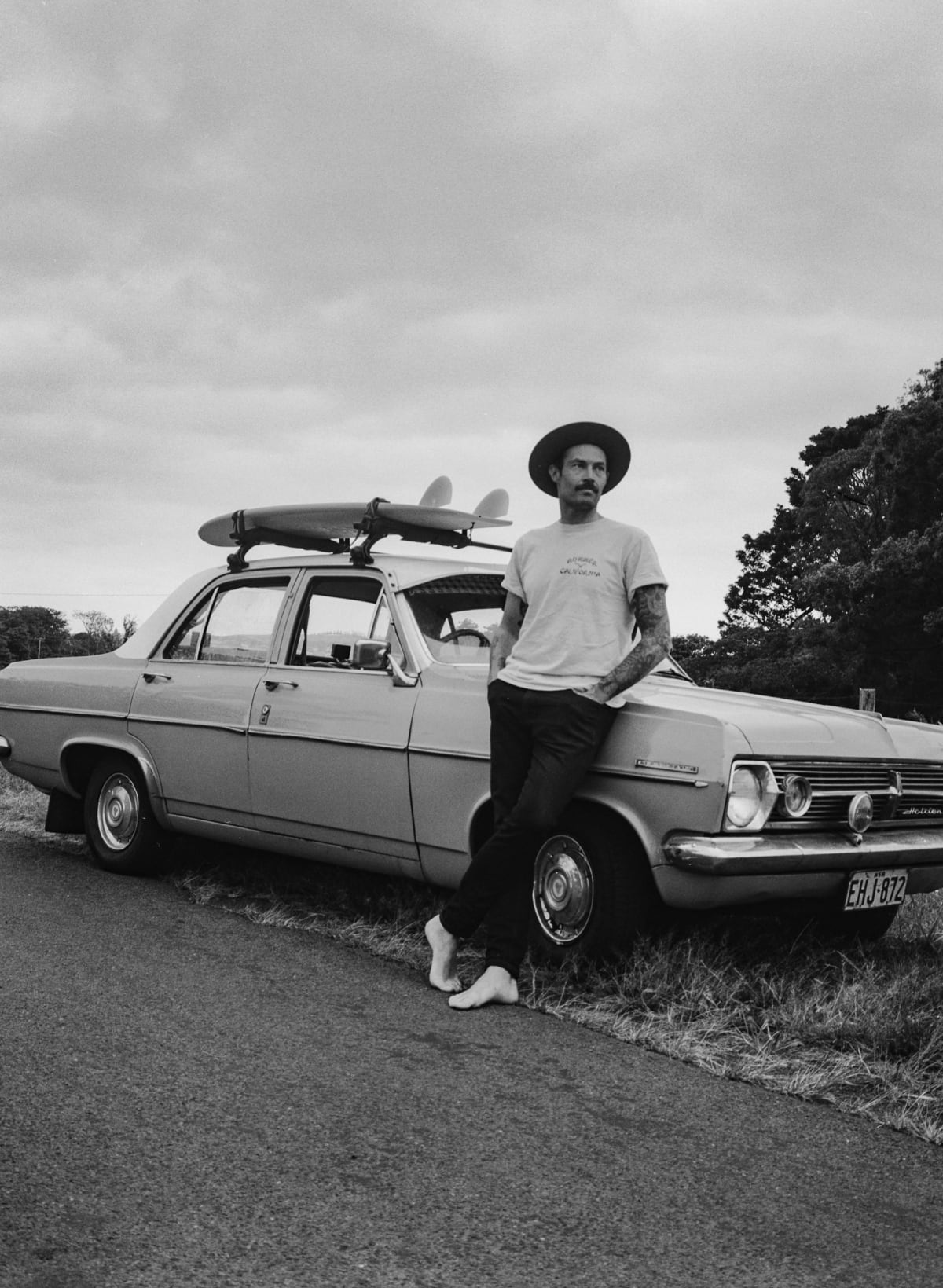 Rob McCann posing with a nice vintage car and a surfboard